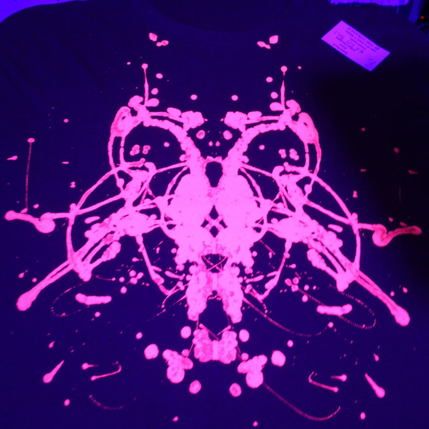 close up of Rorschach, Red cotton T-Shirt with Fluorescent Orange ink blot - 3XL #1 (RR FlO 3XL1) under UV light
