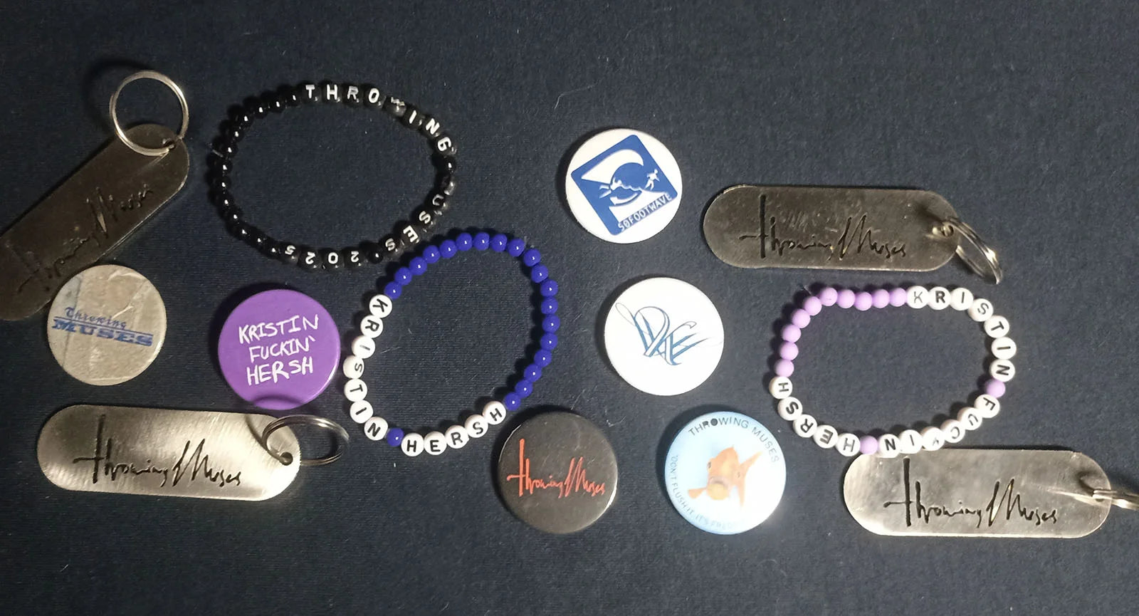 Bracelets, Badges and keychains with Throwing Muses and Kristin Hersh text on a dark surface