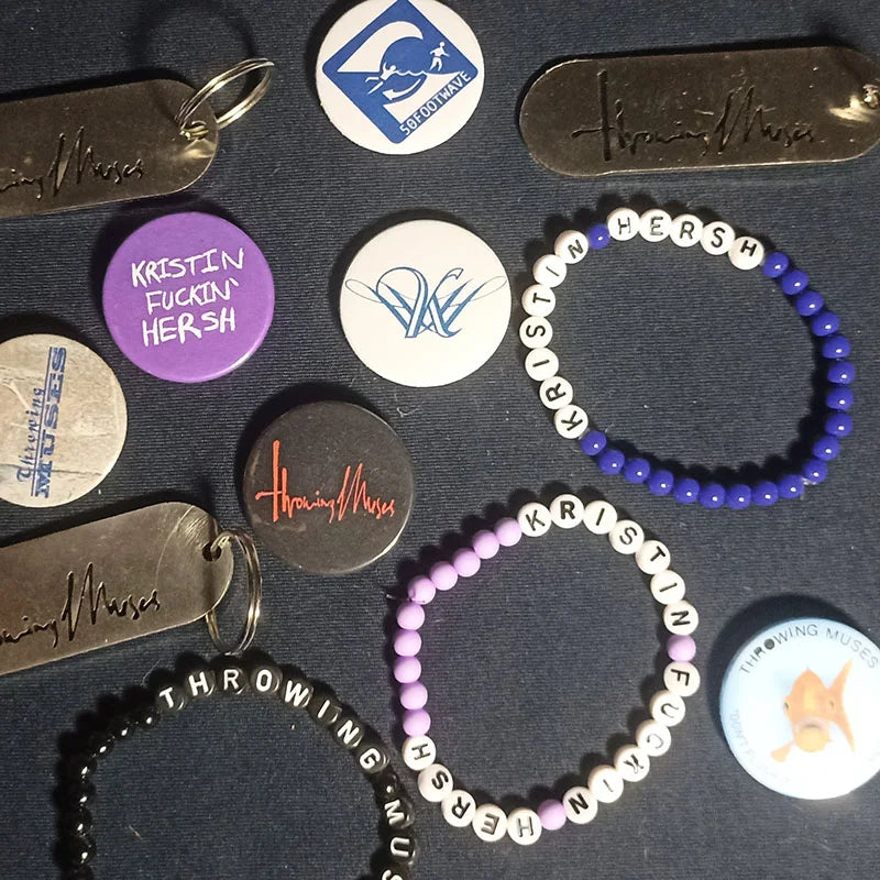 Bracelets, Badges and keychains with Throwing Muses and Kristin Hersh text on a dark surface