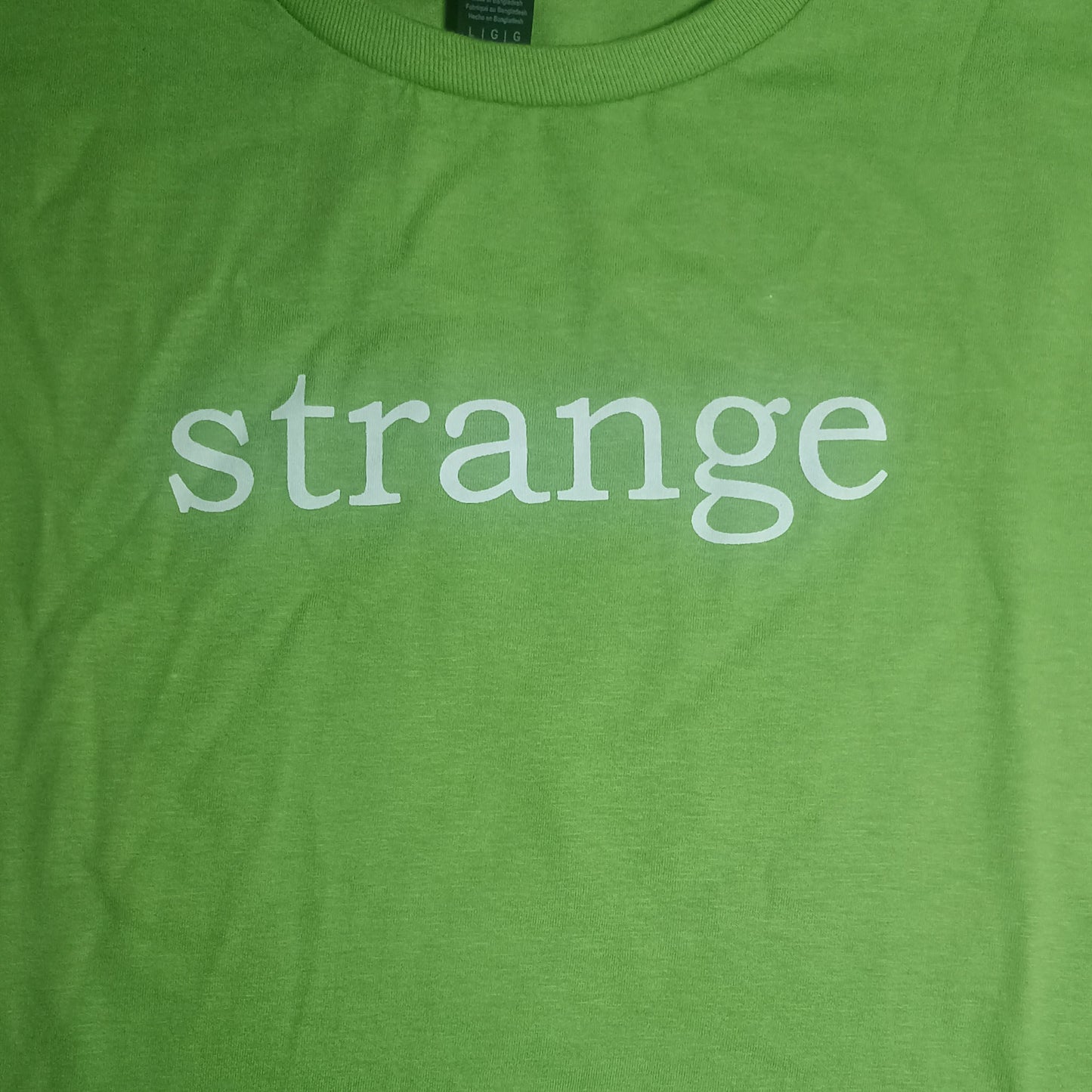 Strange Angel Exclusive Green t-shirt with the word 'strange' printed on it.