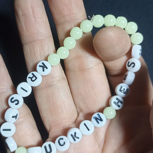 Bracelet with letter beads spelling out 'KRISTIN FN HERSH' on a hand against a dark background, Pearl