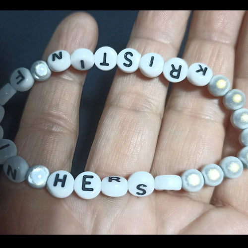 Bracelet with letter beads spelling out 'KRISTIN FN HERSH' on a hand against a dark background, Grey Pearl