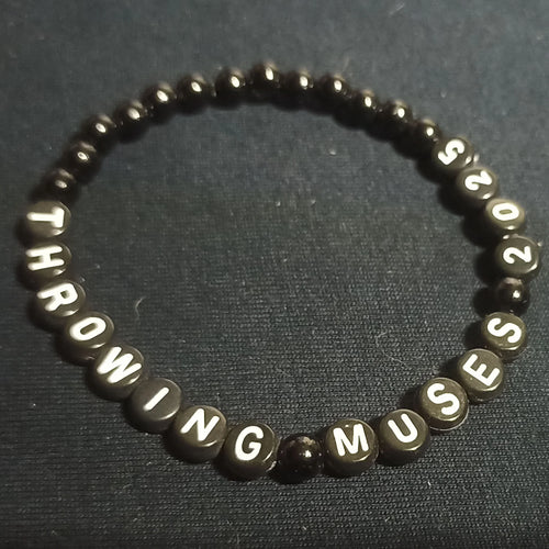 Bracelet with letter beads spelling 'THROWING MUSES 2025' on a dark background from ElRat Designs