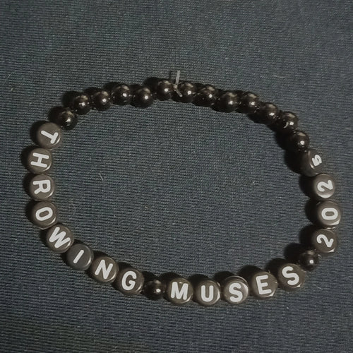 Bracelet with letter beads spelling 'THROWING MUSES 2025' on a dark background from ElRat Designs