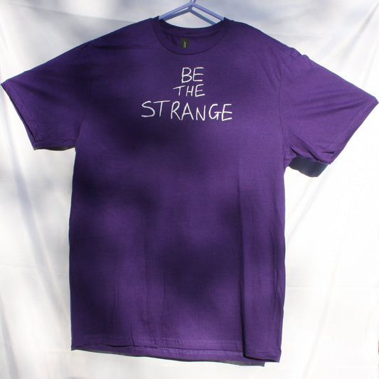 ElRat Designs Original 'Be the Strange' Hand-Printed T-shirt in Purple with White Water-Based Ink. Unique and artistic, featuring a hand-drawn scrawl design. A limited edition piece for those seeking creative expression in fashion