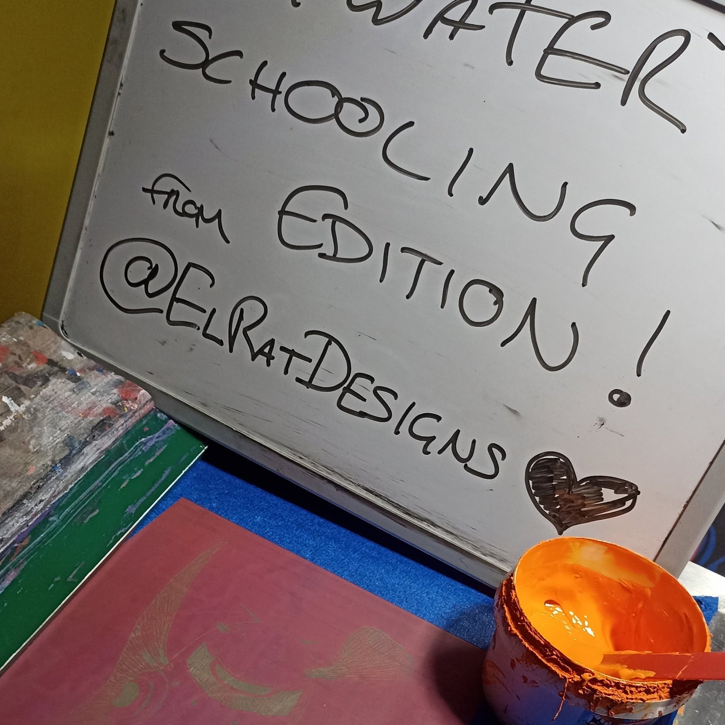 Close-up of screen printing setup for the 'Bywater Schooling' design, with an open tub of vibrant orange, eco-friendly water-based ink. (bywater-schooling-2)